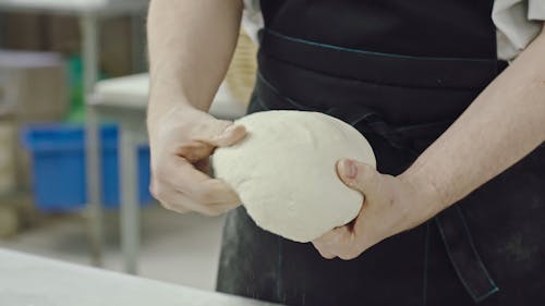 Пекарь показывает свое мастерство в приготовлении теста, готового к выпечке