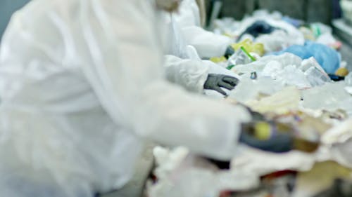 Workers Sorting Out Trash In A Conveyor In A Recycling Plant