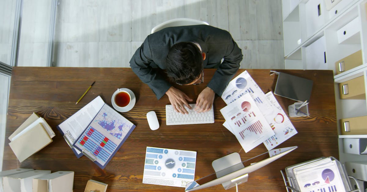 コンピューターを使用して机の上の文書にデータを記録する男性 · 無料の動画素材