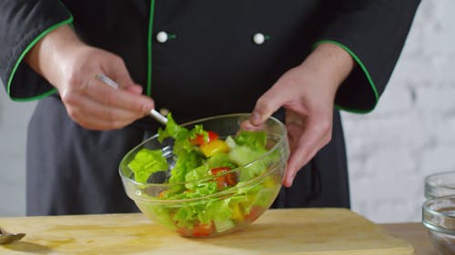 Een Chef Gooit De Groentesalade In Een Kom Om De Dressing Te Verspreiden