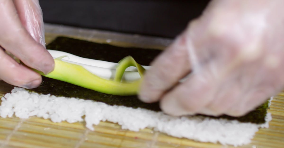 Spreading Down The Ingredients On A Seaweed Wrap To Make A Sushi Roll Spreading Down The Ingredients On A Seaweed Wrap To Make A Sushi Roll