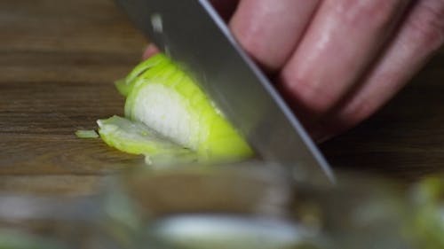 A Person Slicing An Onion Into Diced