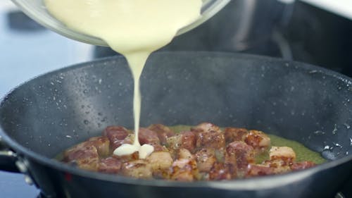 Mixing Heavy Cream To A Frying Bacon Bits To Make A Sauce
