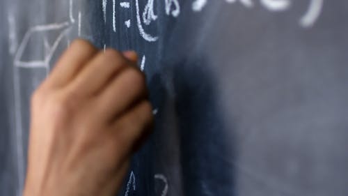 A Man Writing Mathematical Equation On A Blackboard