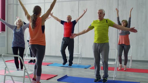 A Woman Fitness Instructor Teaching The Group Of Elderly People Some Exercises Fitted For Them
