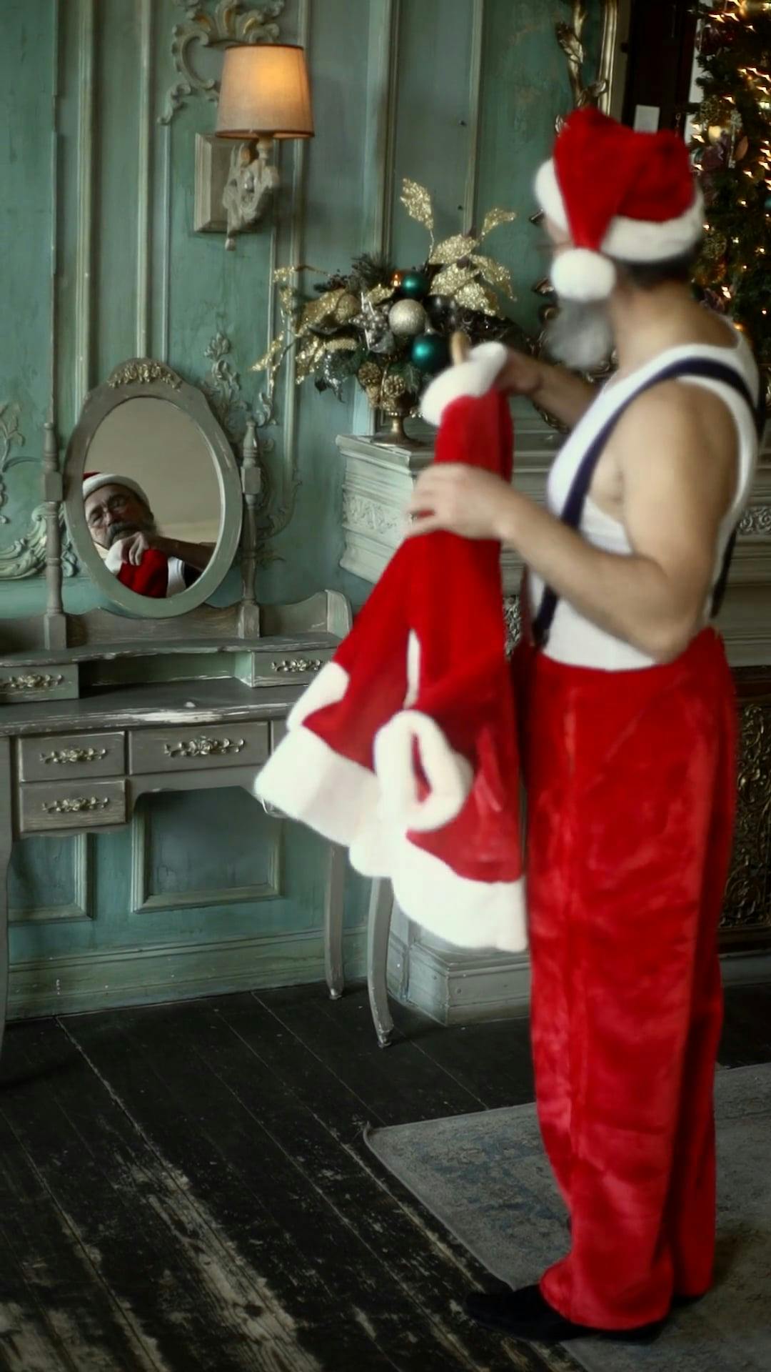 An Elderly Man Looking Himself At A Mirror Holding His Santa Claus ...