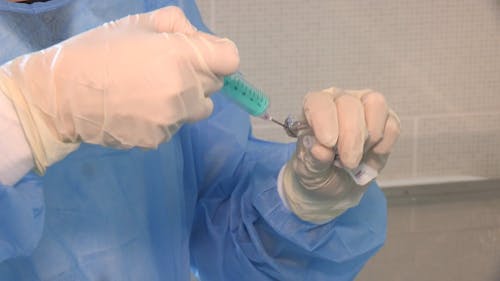 A Medical Practitioner Transferring Liquid Medicine Into A Syringe 