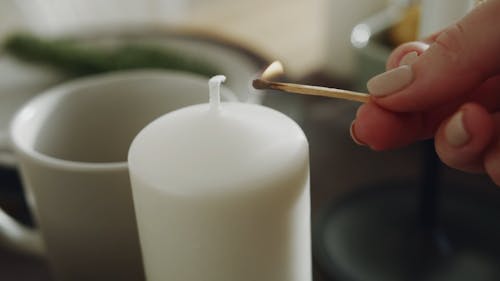 A Person Lighting A Candle With Burning Stick Matches
