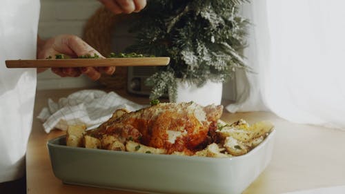 Garnishing A Baked Chicken With Chopped Herbs
