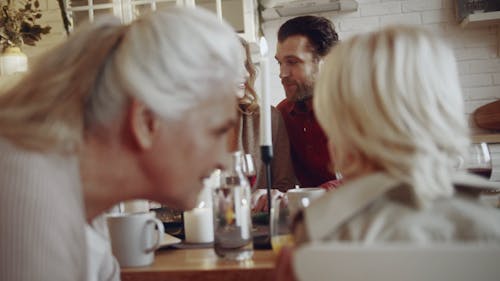 Close-up Footage Of A Grandmother Lovingly Talking To His Grandson Sitting Beside Her On The Dinner Table