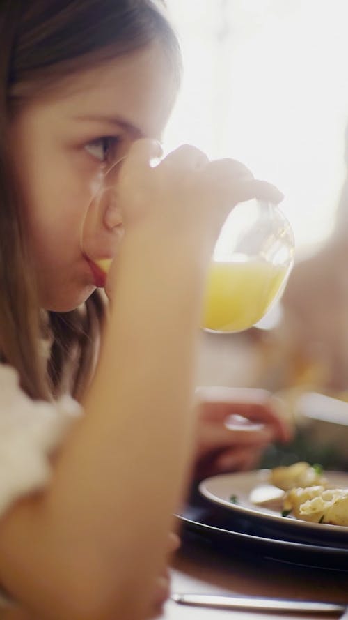 A Child Drinking A Juice From A Crystal Glass