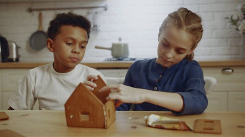 Een Jongen Kijkt Naar Een Meisje Dat Probeert Een Modelhuis Van Koekjes Te Maken