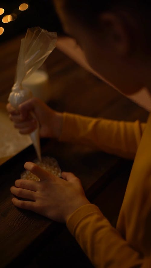 A Girl Decorating A Cookie Using Icing