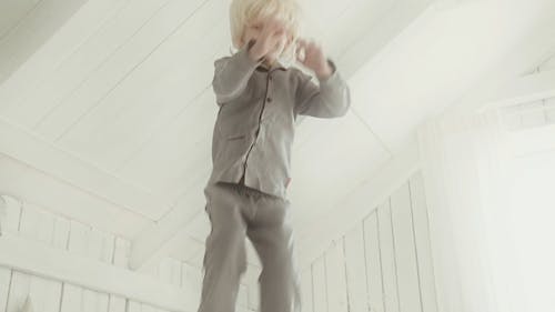 A Boy Jumping Up High And Down In A Bed