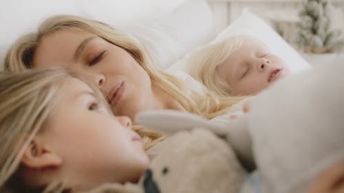 一位母亲带着两个孩子在一起躺在床上的时刻