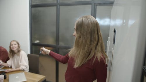 A Woman Writing On A White Board Ideas Pitched In A Business Meeting