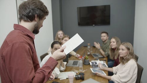 A Man Standing Taking The Lead In A Business Meeting