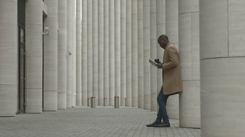 Man Outside A Building Having Coffee While Waiting