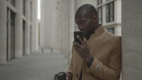 Man Outside A Building Talking Over The Phone And Waving At Someone