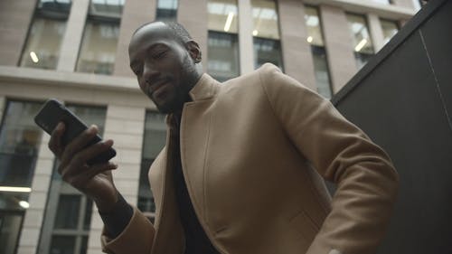 Man Zit Buiten Een Gebouw Terwijl Hij Zijn Telefoon Kijkt En Koffie Drinkt