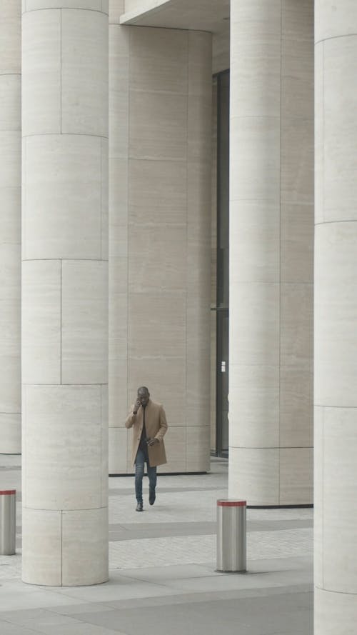 Man Walking Outside A Building Having A Conversation Over The Phone