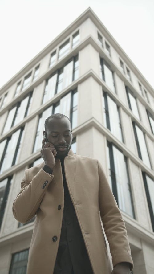 Man Outside A Building Having A Conversation With Someone Over The Phone