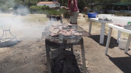 Two Men Grilling A Bunch OF Steaks Outdoor