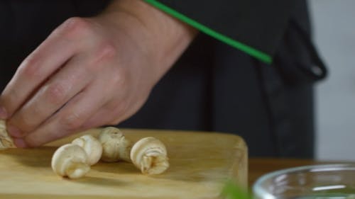 A Person Cutting Fresh Button Mushrooms Into Pieces