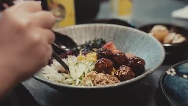 hands mixing colorful asian bowl with chopsticks