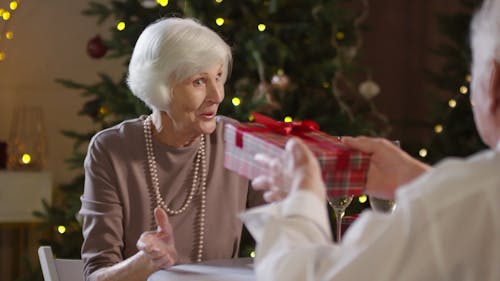 An Elderly Woman Showing Appreciation In Receiving A Gift From An Elderly Man