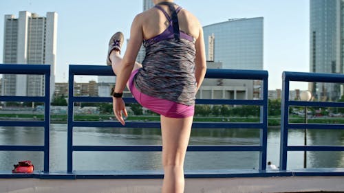 Kobieta Podnosząca Jedną Nogę Nad Poręczą Aby Wykonać ćwiczenia Rozciągające