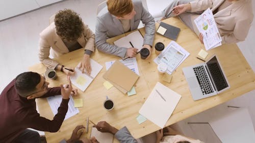 A Group Of People Discussing A Chart In A Business Meeting