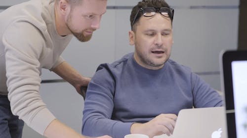 A Man Discusses To His Co-workers A Job He Has Done On His Laptop