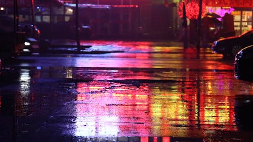 Две женщины с зонтиком стоят посреди пустой улицы дождливой ночью