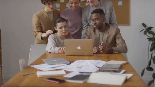 Group Of People Compressed Together Looking At A Laptop 