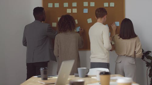 Group Of People Sticking Note Pads On A Baord