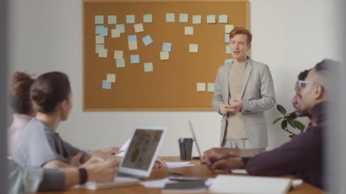 A Man Standing Leading The Discussion In A Business Meeting