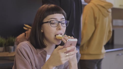 Een Vrouw Die Een Pizza Eet Terwijl Ze Bezig Met Haar Mobiele Telefoon