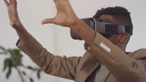 A Man Wearing A Virtually Reality Gear Gesturing With His Hands 