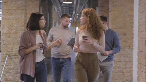 People Walking In The Corridor With Coffee While Having  A  Break