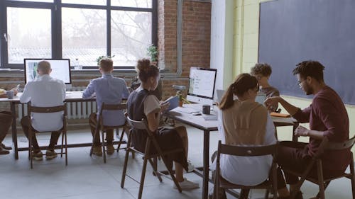 A Group Of People Are Seated And Busy Doing Their Work