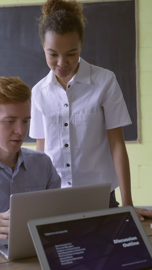 A Man And A Woman Conversing About Work Done Using a Laptop