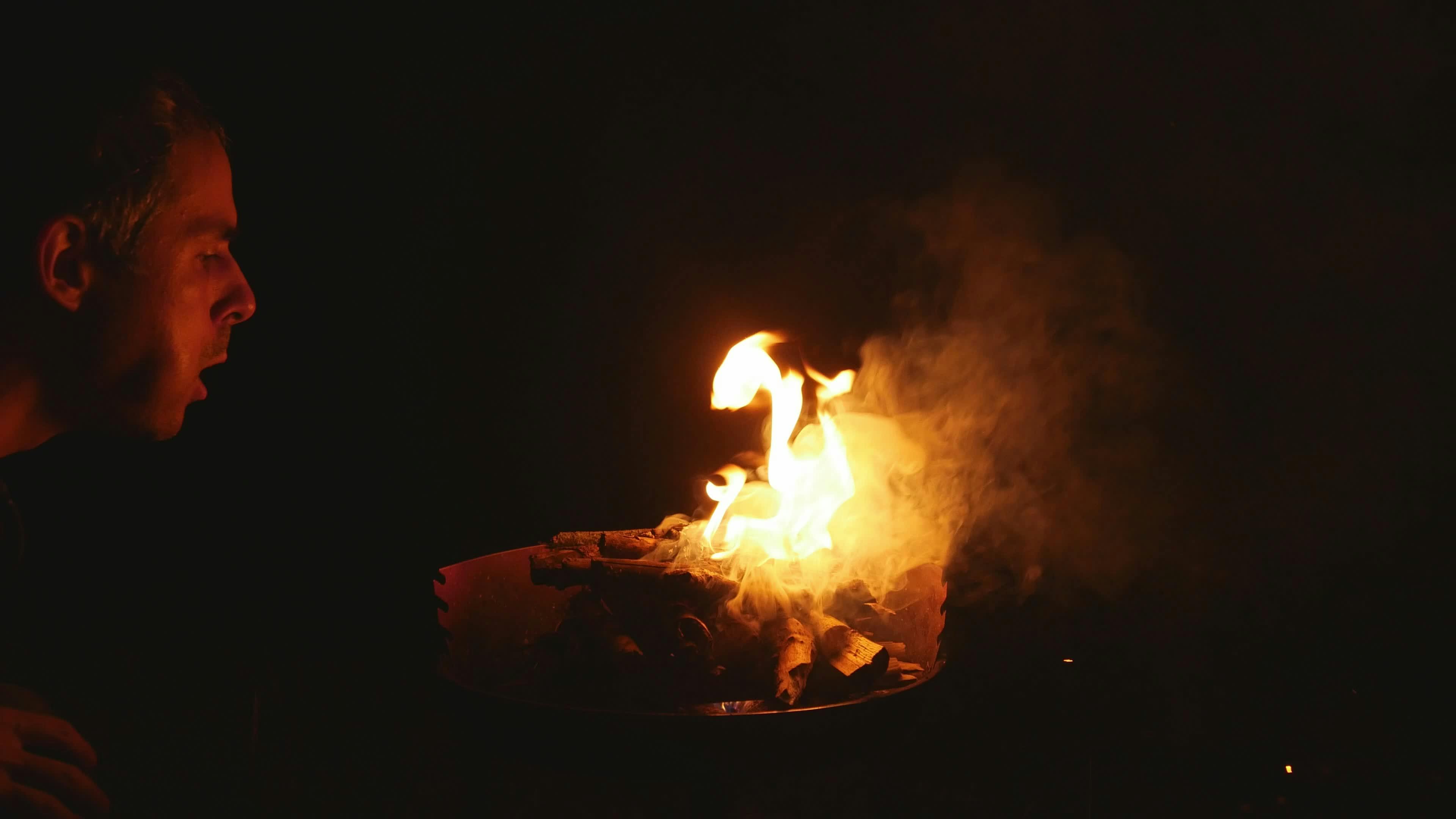 man blowing into fire at night 32632823