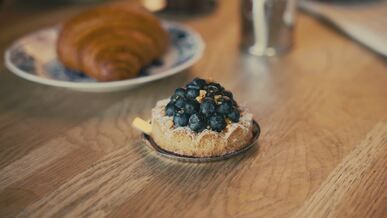 blueberry tart and croissant on wooden table