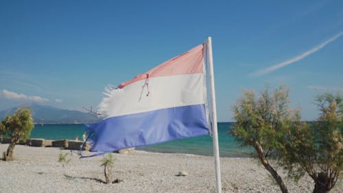 View Of A Beach With Flag Near The Shore