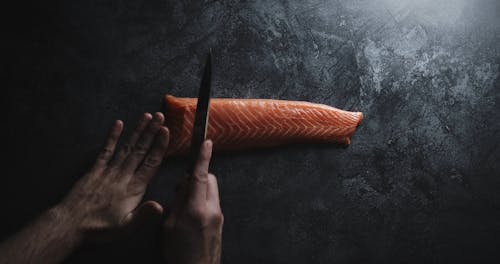 Slicing A Piece From A Slab Of Salmon Meat Using A Knife