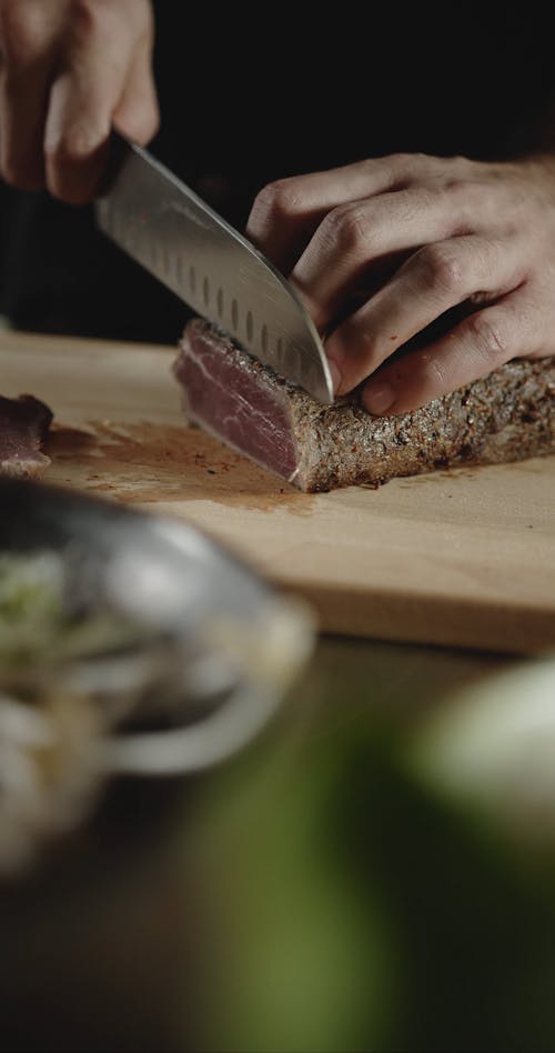 A Person Cutting A Grilled Steak Into Thin Slices