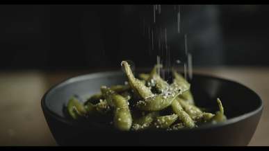 sprinkle of salt on a cooked soy bean pod in a bowl