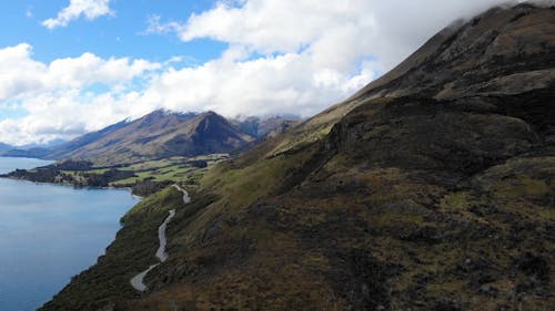 A Road Built On The Foot Of A Mountain Overseeing The Lake