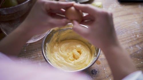Person Adding Egg To A Batter